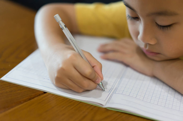 Küçük çocuk el evde ödev yazıyor. Eğitim kavramı - Fotoğraf, Görsel