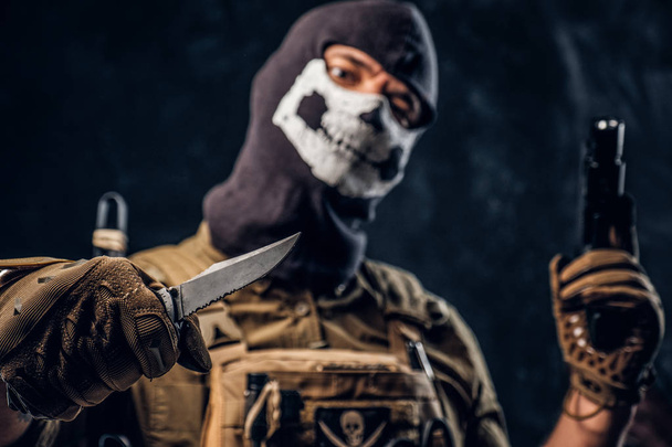 Un terroriste en uniforme militaire et un crâne de cagoule tenant un pistolet et un couteau et regarde la caméra avec un regard menaçant
 - Photo, image