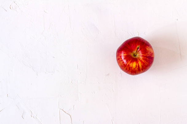 Красное яблоко на белом столе. - Фото, изображение