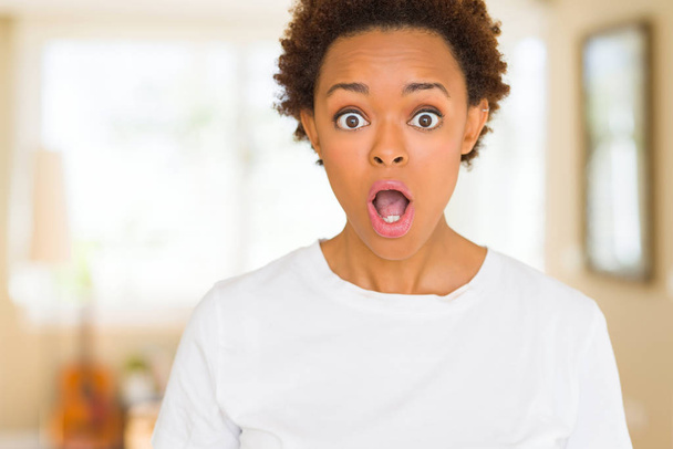 junge schöne afrikanisch-amerikanische Frau trägt legeres weißes T-Shirt Angst und schockiert mit überraschtem Ausdruck, Angst und aufgeregtem Gesicht. - Foto, Bild