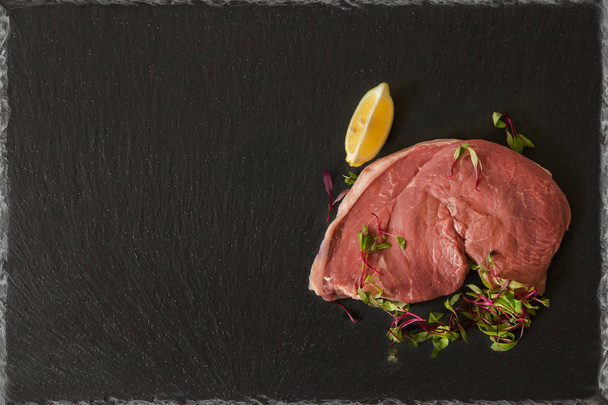 レモン スライスとマイクロ サラダの付け合わせブラック スレート板上生地鶏臀部ステーキ牛肉 - 写真・画像