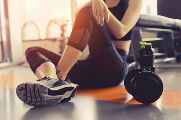 Жінка тренується в фітнес-тренажерному залі, розслабляється, тримаючи пляшку білкового струшування після тренувального спорту з гантелі та здорового способу життя бодібілдингу
. - Фото, зображення