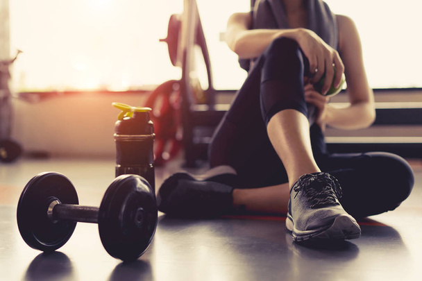 Woman exercise workout in gym fitness breaking relax holding apple fruit after training sport with dumbbell and protein shake bottle healthy lifestyle bodybuilding. - Fotoğraf, Görsel