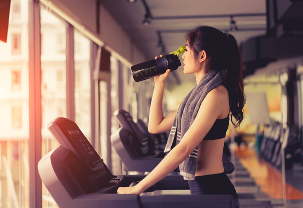 Exercise treadmill cardio running workout at fitness gym of woman taking weight loss with machine aerobic for slim and firm healthy in the morning with drinking protein shake. - Φωτογραφία, εικόνα