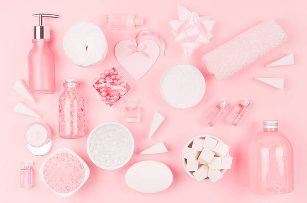 Different cosmetic products and accessories in pink and silver color as decorative pattern on soft light pink background, top view. - Foto, imagen