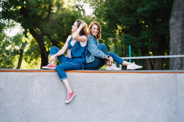 İki mutlu genç kız kaykay parkında oturuyor. - Fotoğraf, Görsel