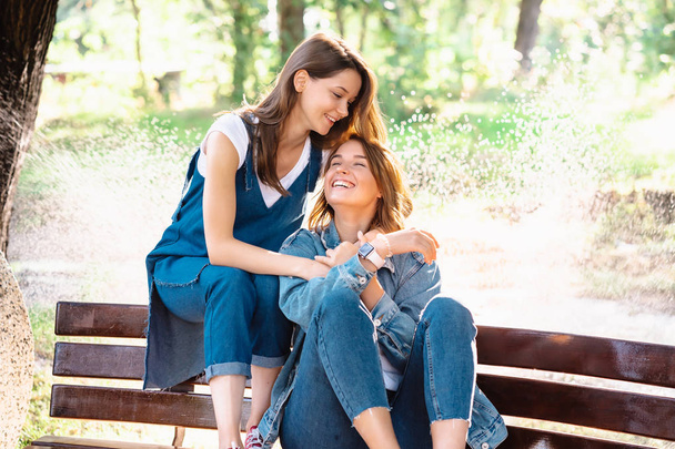 Two beautiful young woman resting on a bench - 写真・画像