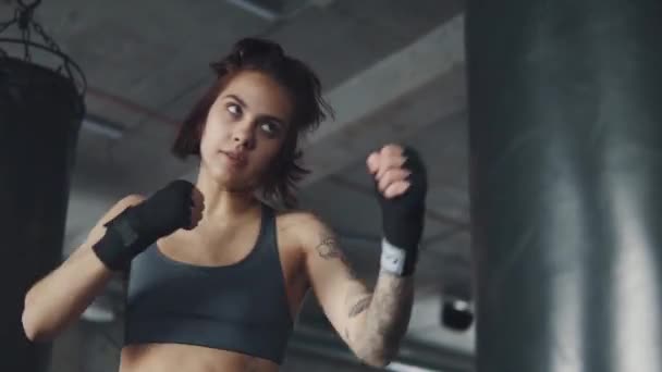 ボクサーの女の子のポートレート、クローズ アップ。フィットネス スタジオで魅力的なキック ボクシング女性トレーニング パンチング バッグ - 映像、動画