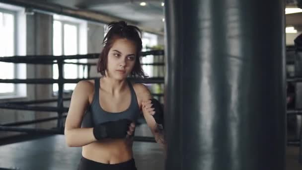 ボクサーの女の子のポートレート、クローズ アップ。フィットネス スタジオで魅力的なキック ボクシング女性トレーニング パンチング バッグ - 映像、動画