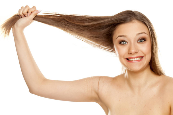 Joven rubia mostrando su largo cabello liso sobre un fondo blanco
 - Foto, imagen