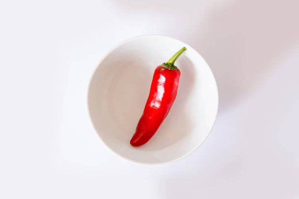 chillies red whole on a white background with a round bowl - Фото, изображение