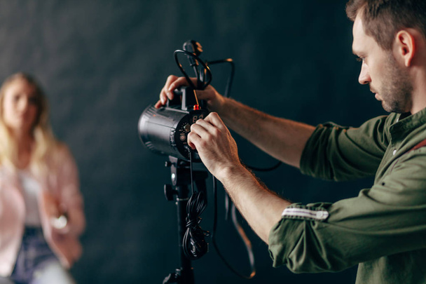 fiatal jóképű férfi dolgozik egy szakmai studio photo flash stroboszkóp. - Fotó, kép
