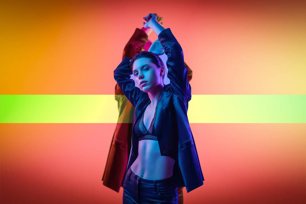 Cinematic night portrait of woman in  neon. High Fashion model girl in colorful bright neon lights posing in studio, portrait of beautiful woman in   jacket, underwear and trousers.  - Photo, Image