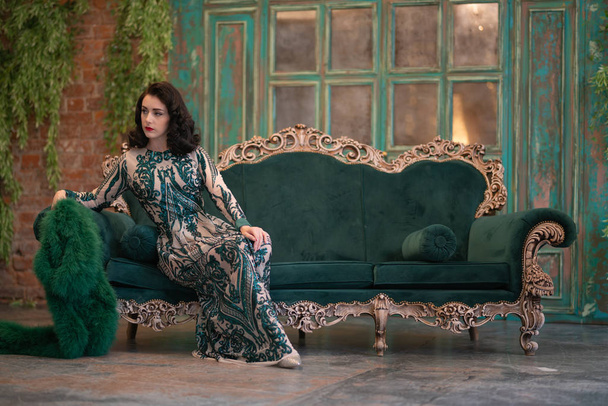 bir lüks uzun pullu dantel şık beyaz kız retro vintage lüks mobilya oda poz onun elinde bir yeşil tüylü boa ile elbise - Fotoğraf, Görsel