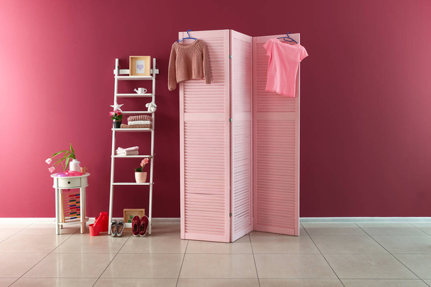 Pantalla plegable rosa con muebles elegantes cerca de la pared de color en la habitación del niño
 - Foto, Imagen