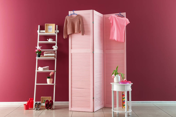 Écran pliant rose avec des meubles élégants près du mur de couleur dans la chambre d'enfant
 - Photo, image