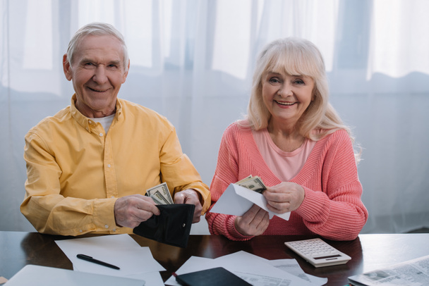 senior couple tenant portefeuille et enveloppe avec de l'argent tout en regardant la caméra
 - Photo, image