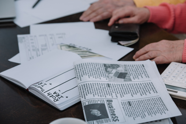 levágott kilátás vezető pár asztalnál ült üzleti napilap, a borítékon "roth ira" betűkkel és a notebook - Fotó, kép