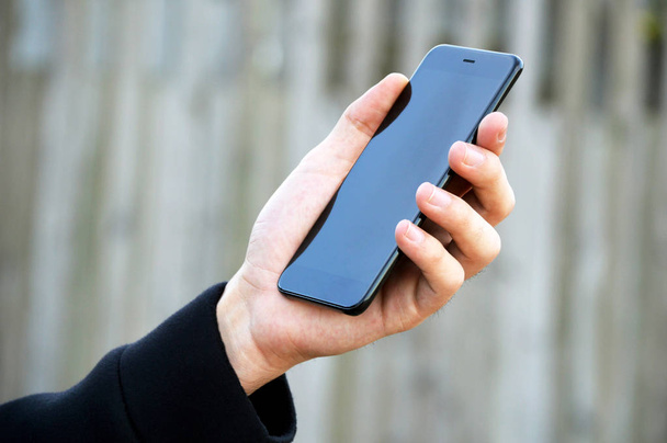 Mano masculina sosteniendo teléfono inteligente
 - Foto, Imagen