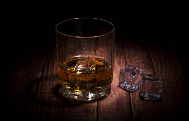 Szklankę whisky i kilka kostek lodu na drewnianym stole - Zdjęcie, obraz