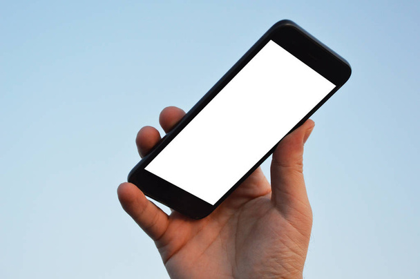Männliche Hand hält Smartphone am Himmel Hintergrund mit Clipping-Pfad - Foto, Bild