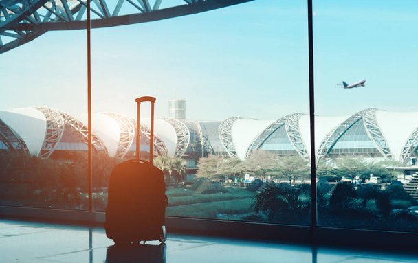 Siluetti matkalaukku, matkatavarat sivuikkunassa lentokentän terminaalin kansainvälinen ja lentokone ulkopuolella lentää lennon sininen taivas matkustaa
  - Valokuva, kuva