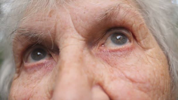 Keresi fel öreg nagymama portréja. Közelről egy idős nő, ráncok, körülöttük szemében - Felvétel, videó