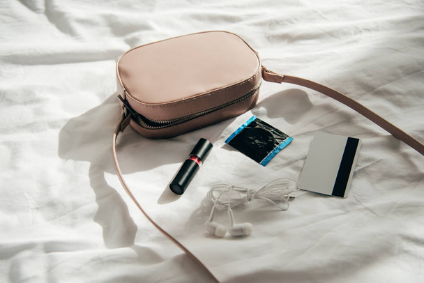 pink bag near lipstick, earphones, credit card and comdom   - Foto, Imagem