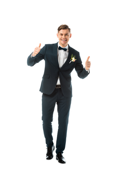 smiling bridegroom in black suit showing thumbs up isolated on white - Foto, Imagem