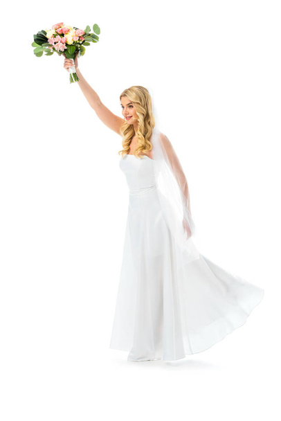 όμορφη νύφη σε κομψό λευκό φόρεμα εκμετάλλευση γαμήλια ανθοδέσμη που απομονώνονται σε λευκό - Φωτογραφία, εικόνα