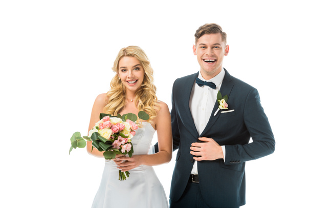 smiling bride with beautiful wedding bouquet, and groom in elegant black suit isolated on white - Photo, Image