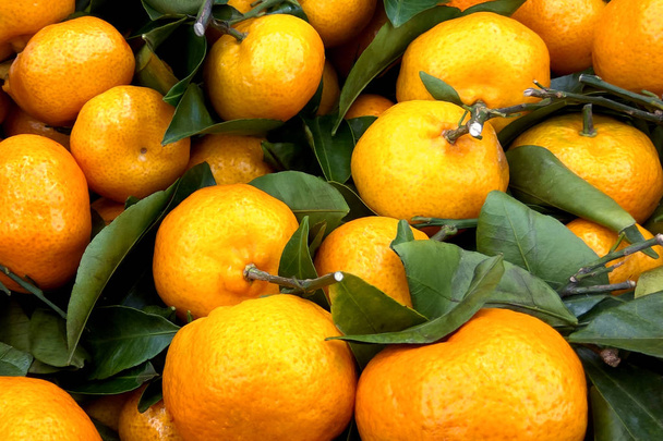 Soczysta pomarańcza mandarynki (pomarańcze, mandarynki, klementynki, owoce cytrusowe) z liści w rynku kosze - Zdjęcie, obraz