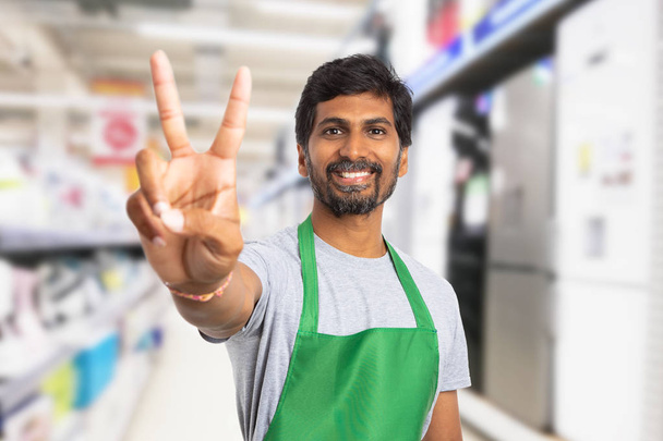 Сотрудник супермаркета показывает победный жест
 - Фото, изображение