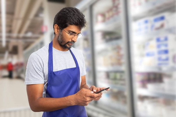 Supermarkt-Mitarbeiter telefoniert per SMS - Foto, Bild
