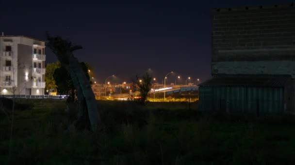 Timelapse notturno di un ponte in citt. Le auto sfrecciano nascoste tra edifici nuovi e case diroccate. - Filmati, video