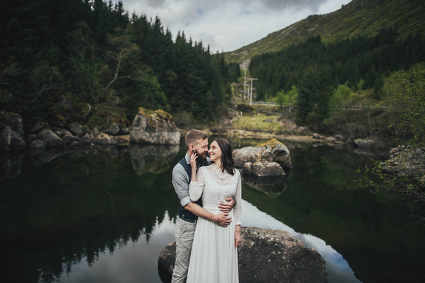 Happy wedding couple travelers hugging on shore of lake, Lofoten, Norway  - Valokuva, kuva