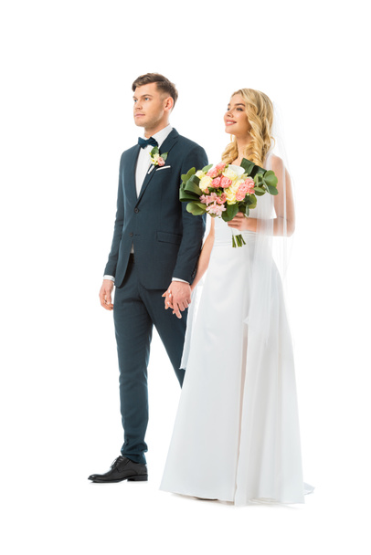 красивая невеста в длинном свадебном платье держась за руки с женихом в элегантном костюме изолированы на белом
 - Фото, изображение