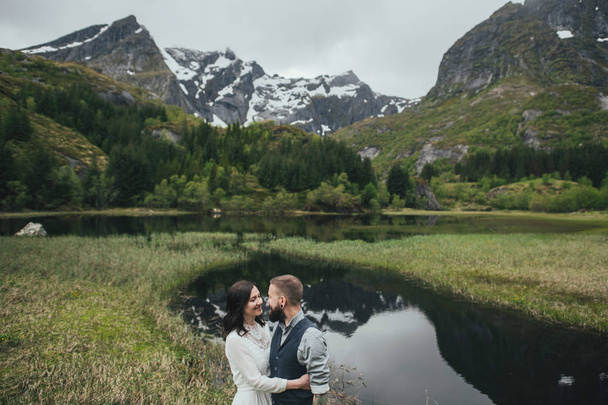 Happy wedding couple travelers hugging on shore of lake, Lofoten, Norway  - Zdjęcie, obraz