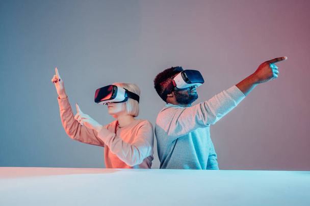 attractive funny man and woman pointing at somewhere while playing VR game - Photo, Image