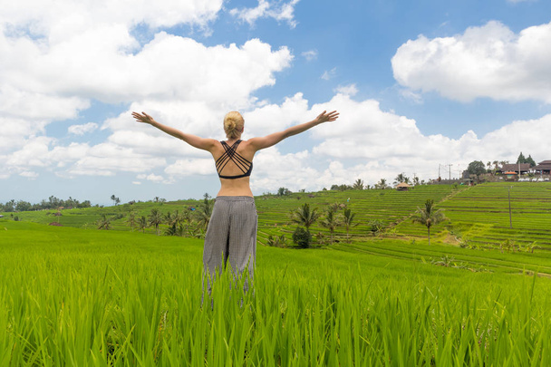 Розслабленої випадковий спортивний жінка, зброї ВОПН в небо, насолоджуючись незайманої природи красиві зелені рисових полів на Балі. - Фото, зображення