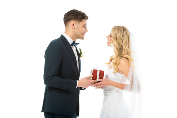 happy groom presenting gift box to smiling bride isolated on white - Photo, Image
