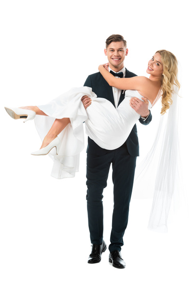 happy handsome groom holding beautiful bride on hands isolated on white - Zdjęcie, obraz