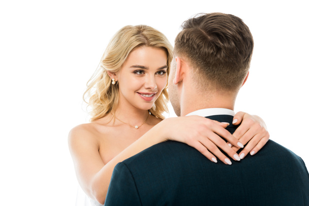 beautiful happy bride with blond hair hugging groom isolated on white - Фото, изображение