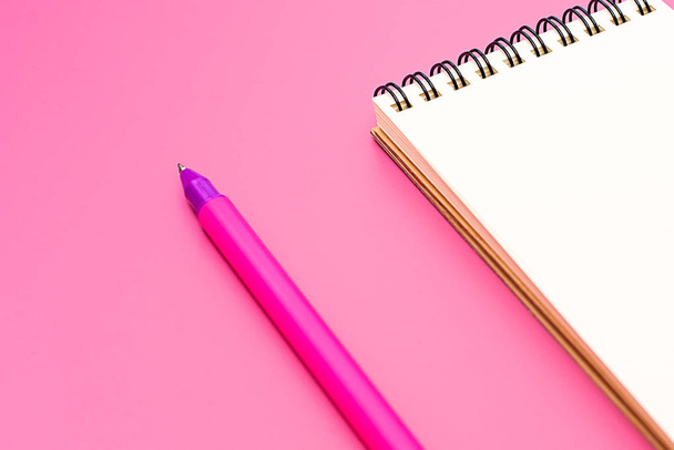 Пустой ноутбук со спиралью для нанесения этикеток и ручки на розовый фон
 - Фото, изображение