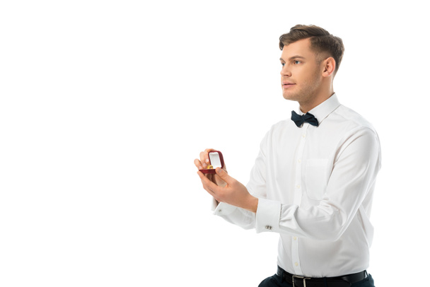 όμορφος groom κρατώντας δώρο κουτί με δαχτυλίδι γάμου που απομονώνονται σε λευκό - Φωτογραφία, εικόνα
