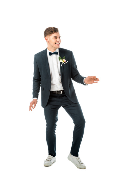novio alegre bailando en traje elegante negro y zapatillas blancas aisladas en blanco
 - Foto, Imagen