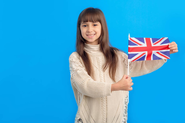 Little girl with flag of United Kingdom on a blue background. Learn English. Schoolgirl, study abroad, international language courses. Flag of Great Britain. - Zdjęcie, obraz