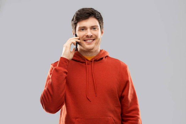 young man in red hoodie calling on smartphone - Foto, Imagen