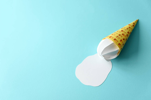 Melted paper vanilla ice-cream cone on blue background. Copy space. Creative or art food concept - Foto, Imagem