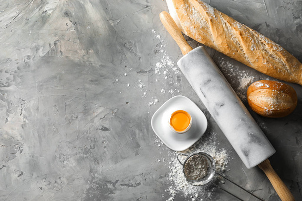 Productos de panadería con rodillo e ingredientes para masa sobre fondo gris
 - Foto, Imagen